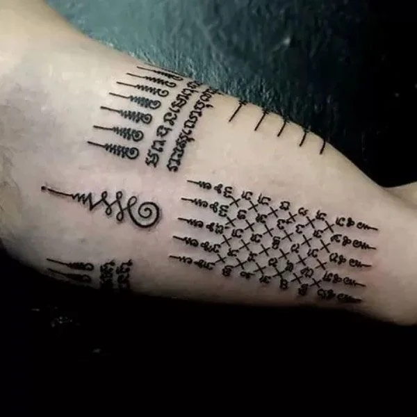 Hình xăm khmer trên cánh tay với cột chữ và hình yantra