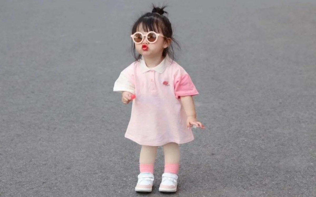 Bé gái thời trang với kính râm và váy hồng dạo phố