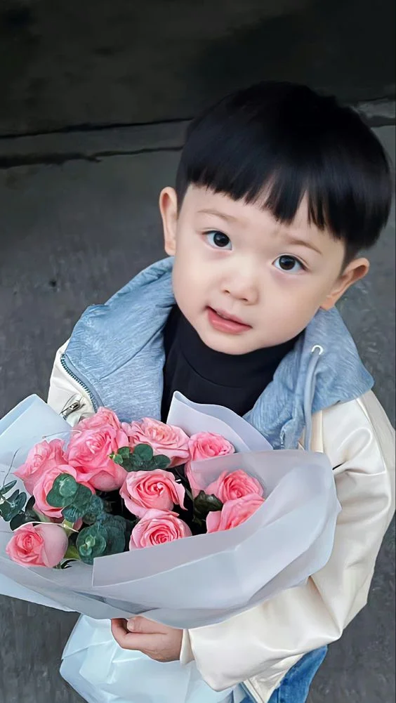 Hình ảnh em bé trai cầm bó hoa hồng hồng tặng mẹ đáng yêu