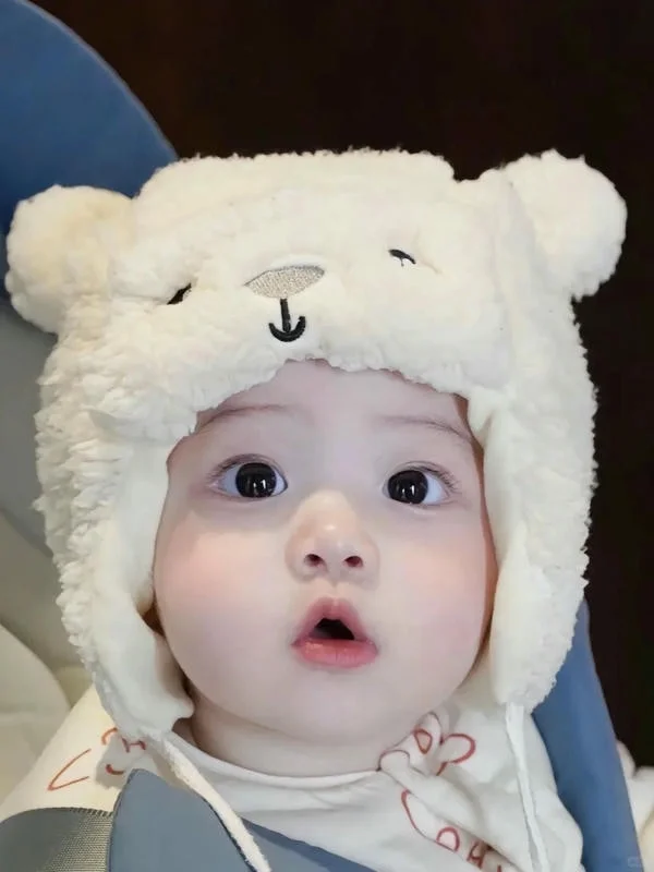 Hình ảnh em bé đội mũ gấu trắng bông tròn trĩnh mắt to tròn
