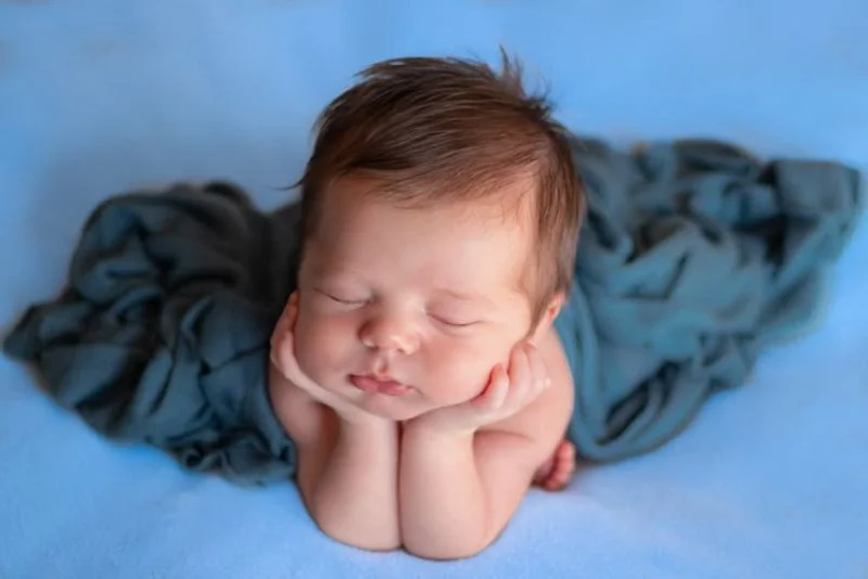 hình em bé dễ thương bebé mới sinh ngủ say trên chăn xanh nền xanh da trời