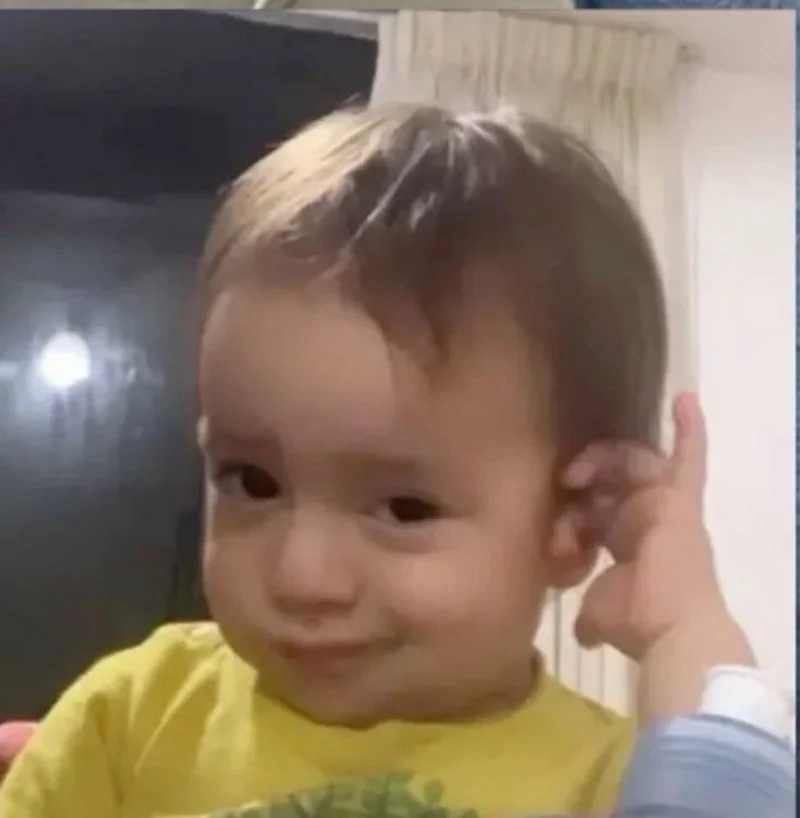 ảnh em bé dễ thương mặc áo vàng chạm tai