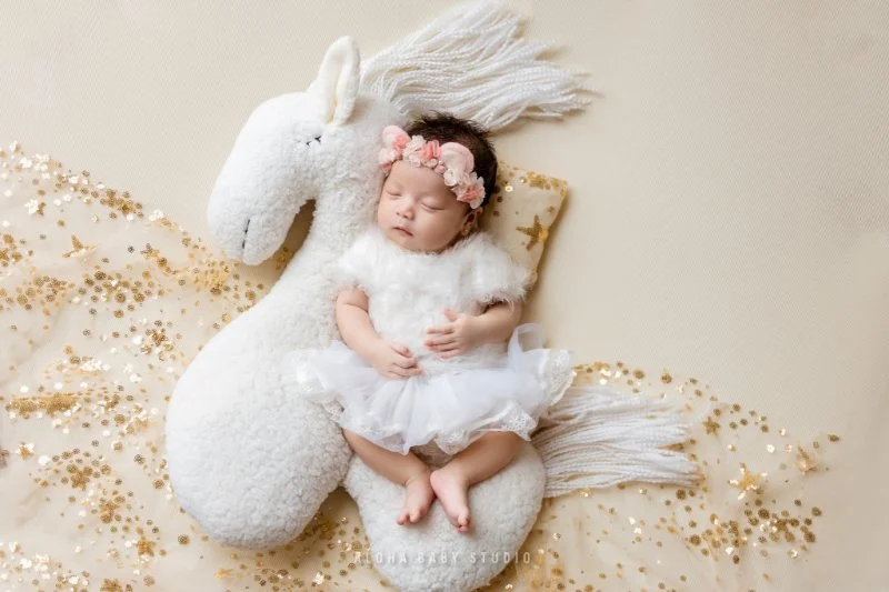 hình em bé dễ thương bé gái ngủ trên búp bê lộc einheit trắng giữa cát vàng