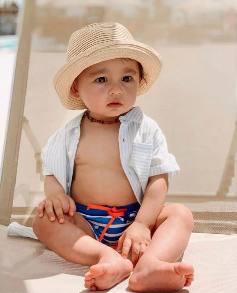 hình em bé dễ thương trai mặc nón rơm và áo trắng ngồi chụp ảnh